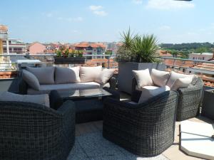 a patio with wicker chairs and couches on a roof at Residhome Arcachon Plazza in Arcachon