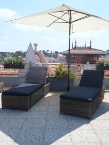 two wicker chairs sitting under an umbrella on a roof at Residhome Arcachon Plazza in Arcachon