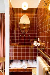 a brown tiled bathroom with a tub and a mirror at Suites 23 in Cassis