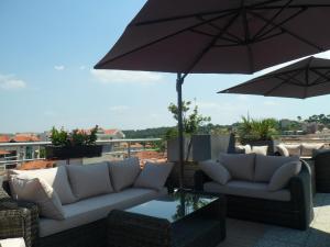 a patio with two couches and an umbrella at Residhome Arcachon Plazza in Arcachon