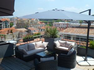 a patio with two couches and an umbrella on a roof at Residhome Arcachon Plazza in Arcachon