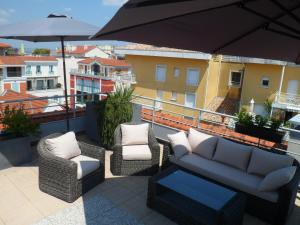 a patio with a couch and chairs and an umbrella at Residhome Arcachon Plazza in Arcachon