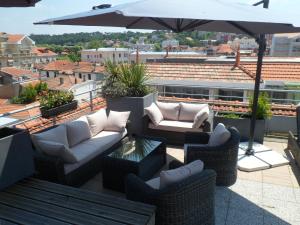 a patio with couches and an umbrella on a roof at Residhome Arcachon Plazza in Arcachon