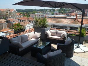 a patio with couches and an umbrella on a roof at Residhome Arcachon Plazza in Arcachon