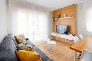 a living room with a couch and a table and a television at Magnifico apartamento en Llanes in Llanes
