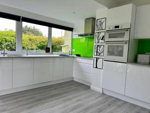 a kitchen with white cabinets and a large window at Sundial Cottage in Newton Abbot