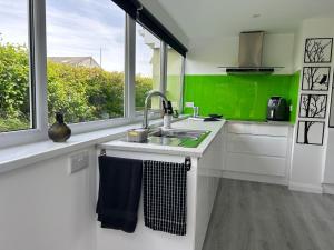 a white kitchen with a sink and a window at Sundial Cottage in Newton Abbot