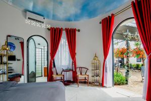Phú ThạnhにあるTrulli Villa Homestay Đà Lạtの赤いカーテン、テーブルと椅子が備わる客室です。