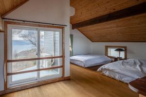 a bedroom with two beds and a large window at Oceanic House TAMATEBAKO in Ito