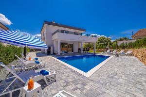 a swimming pool with chairs and an umbrella and a house at Vila KATHARINA s privatnim bazenom in Žgaljić