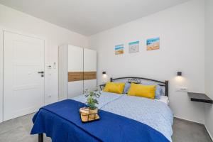 a bedroom with a bed with a blue blanket and yellow pillows at Vila KATHARINA s privatnim bazenom in Žgaljić