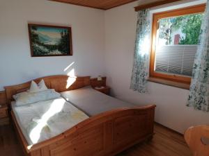 1 dormitorio con cama de madera y ventana en Gästehaus Holzfeind, en Hermagor