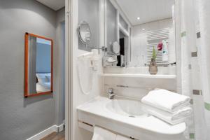 Baño blanco con lavabo y espejo en Select Hotel Friedrichshafen en Friedrichshafen