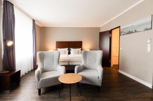 una camera d'albergo con due sedie e un letto di Select Hotel Friedrichshafen a Friedrichshafen