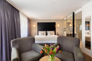 um quarto de hotel com duas cadeiras e uma cama em Select Hotel Friedrichshafen em Friedrichshafen