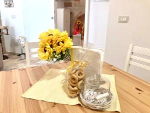une table avec un vase de fleurs jaunes et un vase de biscuits dans l'établissement Antica Pietra, à Polignano a Mare