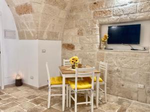 - une salle à manger avec une table, des chaises et une télévision dans l'établissement Antica Pietra, à Polignano a Mare