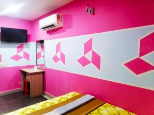 a room with a pink wall with a bed and a tv at DE GLORY HOTEL UsJ 21 in Subang Jaya