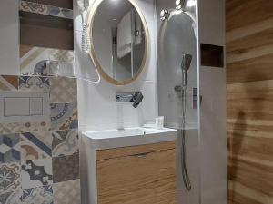 a bathroom with a sink and a shower with a mirror at Apartamenty i Mieszkania Wakacyjne in Chałupy