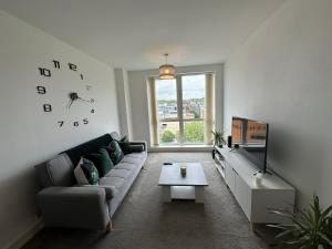 ein Wohnzimmer mit einer Couch und einer Uhr an der Wand in der Unterkunft Luxury 1 Bed Apartment Hemel Hempstead Sleeps 4 Luton Airport Nearby in Hemel Hempstead