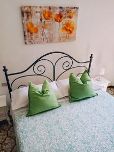 sypialnia z łóżkiem z 2 zielonymi poduszkami w obiekcie Affittacamere Chiti Melania w mieście San Gimignano