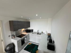 eine kleine Küche mit weißen Schränken und einer Spüle in der Unterkunft Luxury 1 Bed Apartment Hemel Hempstead Sleeps 4 Luton Airport Nearby in Hemel Hempstead
