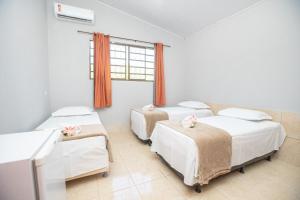 ein Zimmer mit drei Betten und einem Fenster in der Unterkunft Refúgio de Lazer: Chácara c/ Espaço e Conforto in Caldas Novas