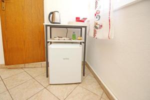 a small white refrigerator under a shelf in a room at Room Rose in Baška