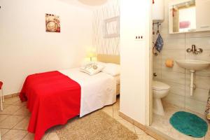 a bedroom with a bed and a sink and a toilet at Room Rose in Baška