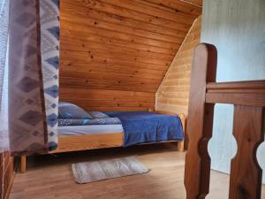 a bed in a room with a wooden wall at Domek u Marysi in Bukowiec