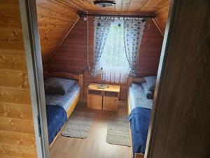 a small room with two beds and a window at Domek u Marysi in Bukowiec