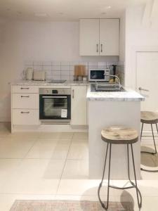 ブライトン＆ホーブにあるStylish & Central, Ideal Beach Retreatの白い家電製品とスツール2つが備わるキッチン
