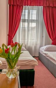 a bedroom with two beds and a vase of flowers on a table at Hotel Růžek in Hranice