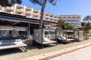 een rij ligstoelen voor een gebouw bij Invisa Hotel Club Cala Verde in Es Figueral Beach