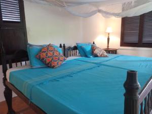 een bed met blauwe lakens en kussens erop bij Madakani House in Lamu