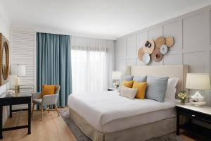 a bedroom with a large white bed and a desk at Corinthia St George's Bay in St. Julianʼs