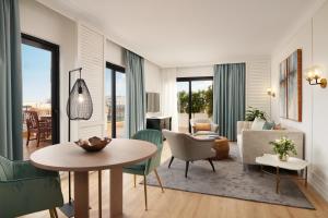 a living room with a table and chairs at Corinthia St George's Bay in St. Julianʼs