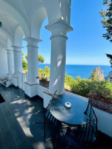 una mesa en un porche con el océano al fondo en Monacone vista mare, en Capri