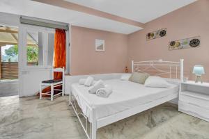 een witte slaapkamer met een bed en een bureau bij Tasoula Studio with garden view in Nikiana