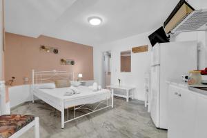 een witte kamer met een bed en een keuken bij Tasoula Studio with garden view in Nikiana +16 foto's