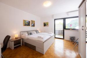 a white bedroom with a bed and a window at Apartment Panorama & Bella Vista in Bohinjska Bela