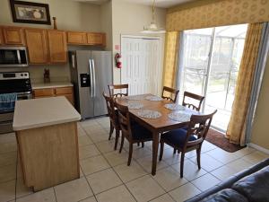a kitchen with a table and chairs and a kitchen with a refrigerator at Spacious 7 BR, 4,5 BR Retreat with Pool 164 condo in Kissimmee