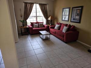 a living room with two red couches and a tile floor at Spacious 7 BR, 4,5 BR Retreat with Pool 164 condo in Kissimmee