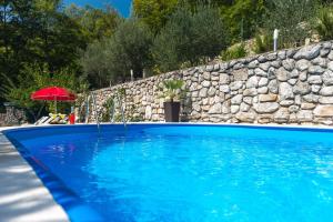 a blue swimming pool next to a stone wall at Haus Karin in Lovran