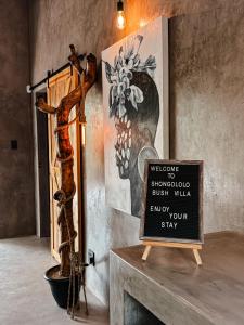 a sign in a room with a tree and a wall at Shongololo Bush Villa in Marloth Park