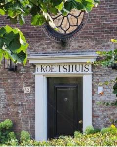 Una señal que dice "kostitución" por encima de una puerta negra. en Koetshuis aan het water 3 bedroom villa, en Voorburg