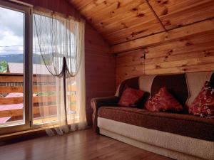 ein Wohnzimmer mit einem Sofa und einem großen Fenster in der Unterkunft "У Яслигана" in Pilipets
