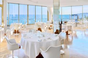 un restaurant avec des tables et des chaises blanches et l'océan dans l'établissement Le Petit Nice - Passedat, à Marseille