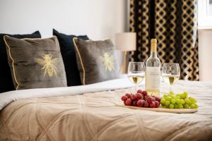 uma bandeja de uvas e copos de vinho numa cama em Lumina apart Manufaktura em Lódź