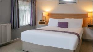 a bedroom with a large white bed with a purple pillow at Tor Park Hotel, Sure Hotel Collection by Best Western in Torquay